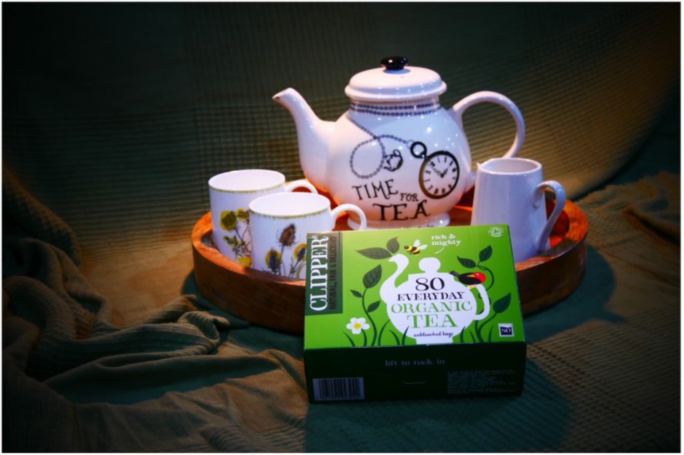 A photo of a teapot, cups and a box of teabags on a tray